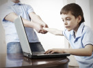 Father dragging son from the computer. Parent pulling child from laptop. Computer Addiction
